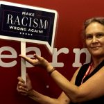 Debby holding a blue sign reading "Make racism WRONG AGAIN!"