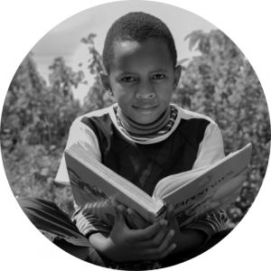 black boy holding book sitting cross legged on ground reading