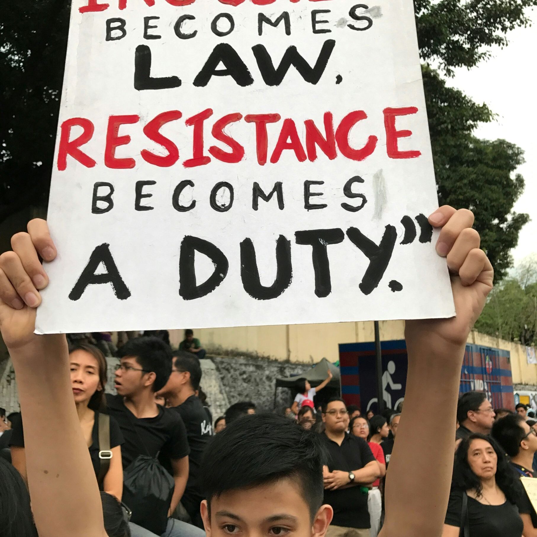 protestor holds up a sign saying "when injustice becomes law, resistance becomes a duty."